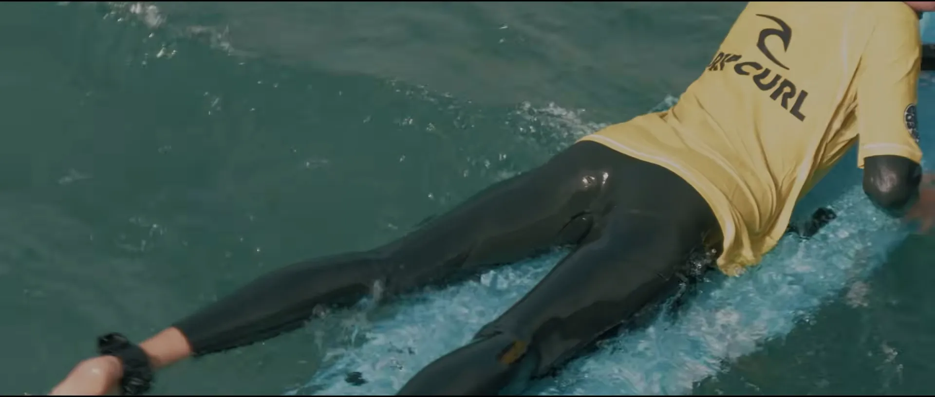 Close shot of Rowan paddling on his board
