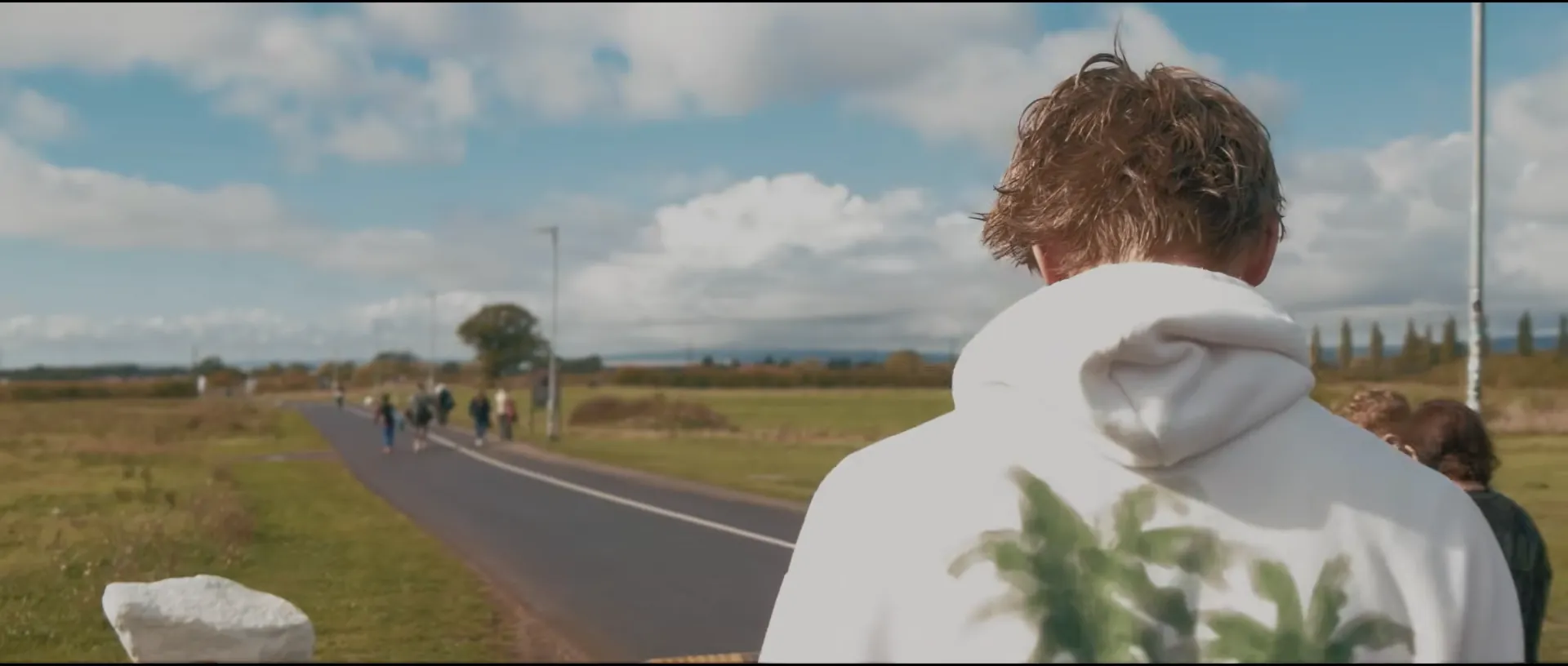 Rowan in a white hoodie looking across a field