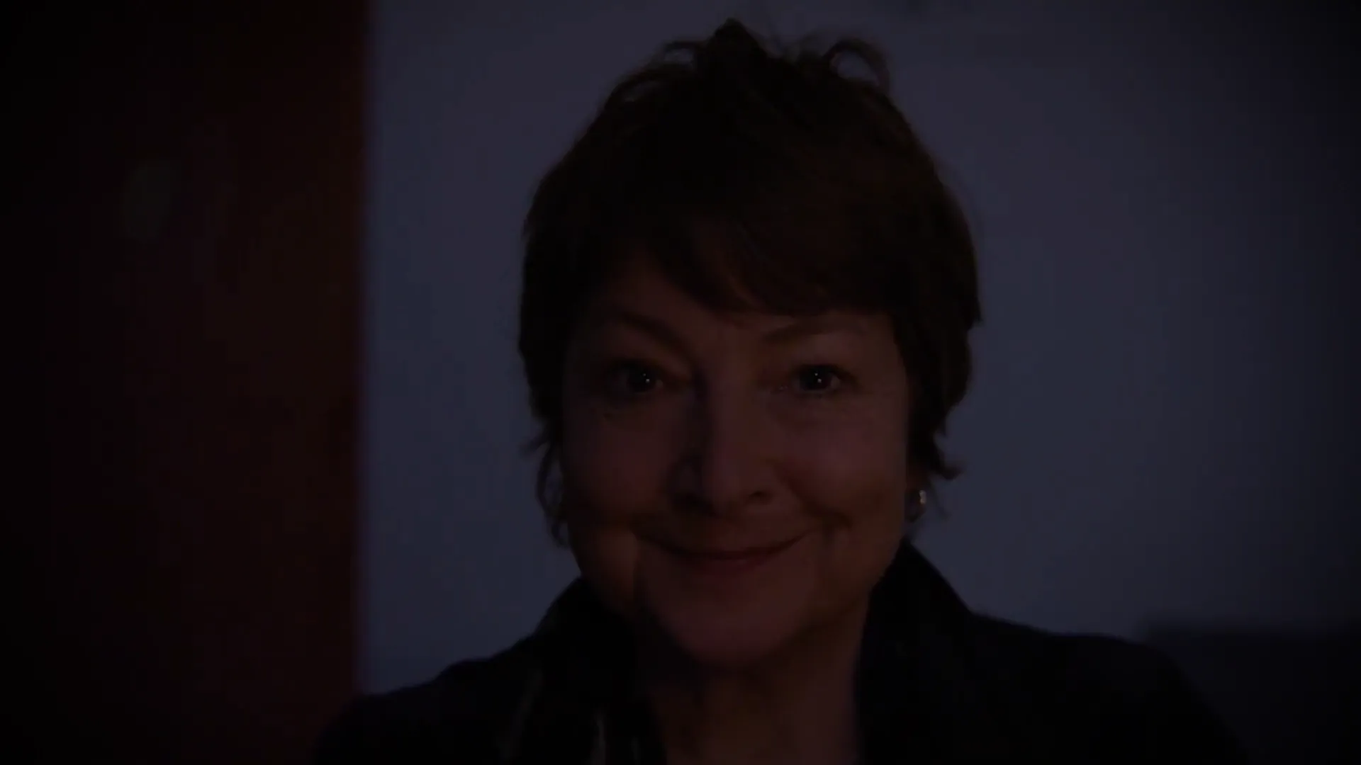 An older woman smiling in the dark