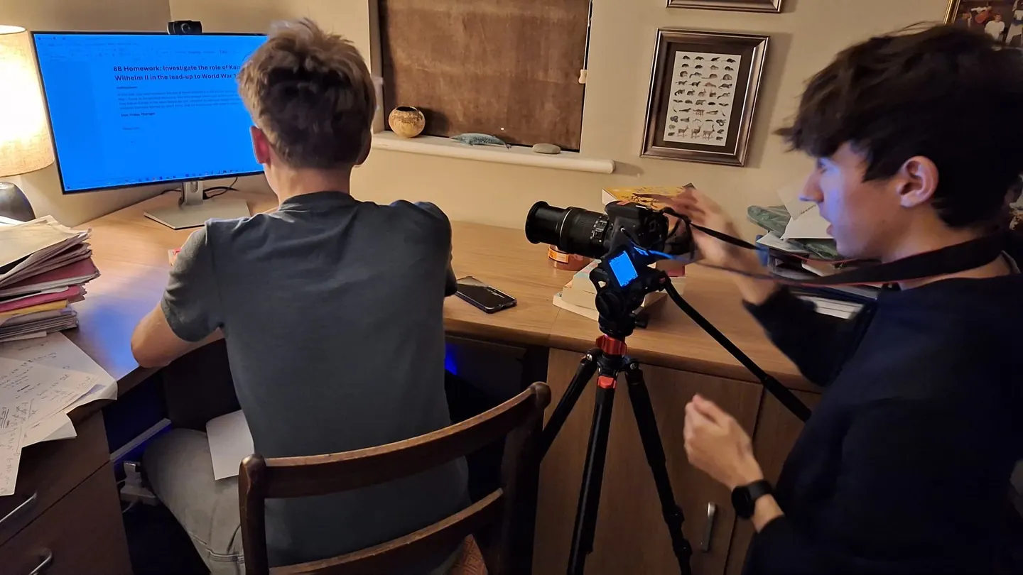 Camera on tripod behind my brother at the desk