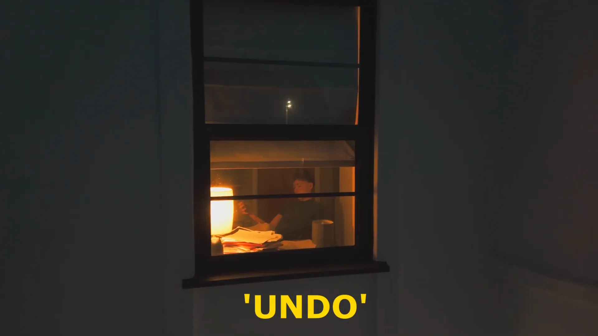 Drone establishing shot of the lit bedroom window at night